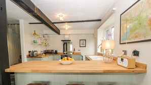 A modern kitchen with a wooden island, bar stools, a map on the wall, and a radio. - Waterside (Ravenglass)