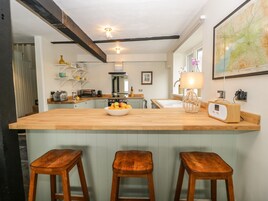 Cozinha moderna com ilha de madeira, banquetas, um mapa na parede e um rádio.