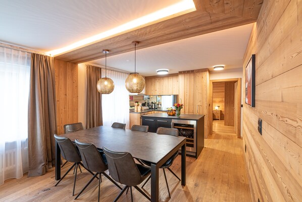 A modern kitchen with wooden cabinets, a central island, and pendant lighting. - Haus Mirador by Zermatt Premium Apartments (Zermatt)