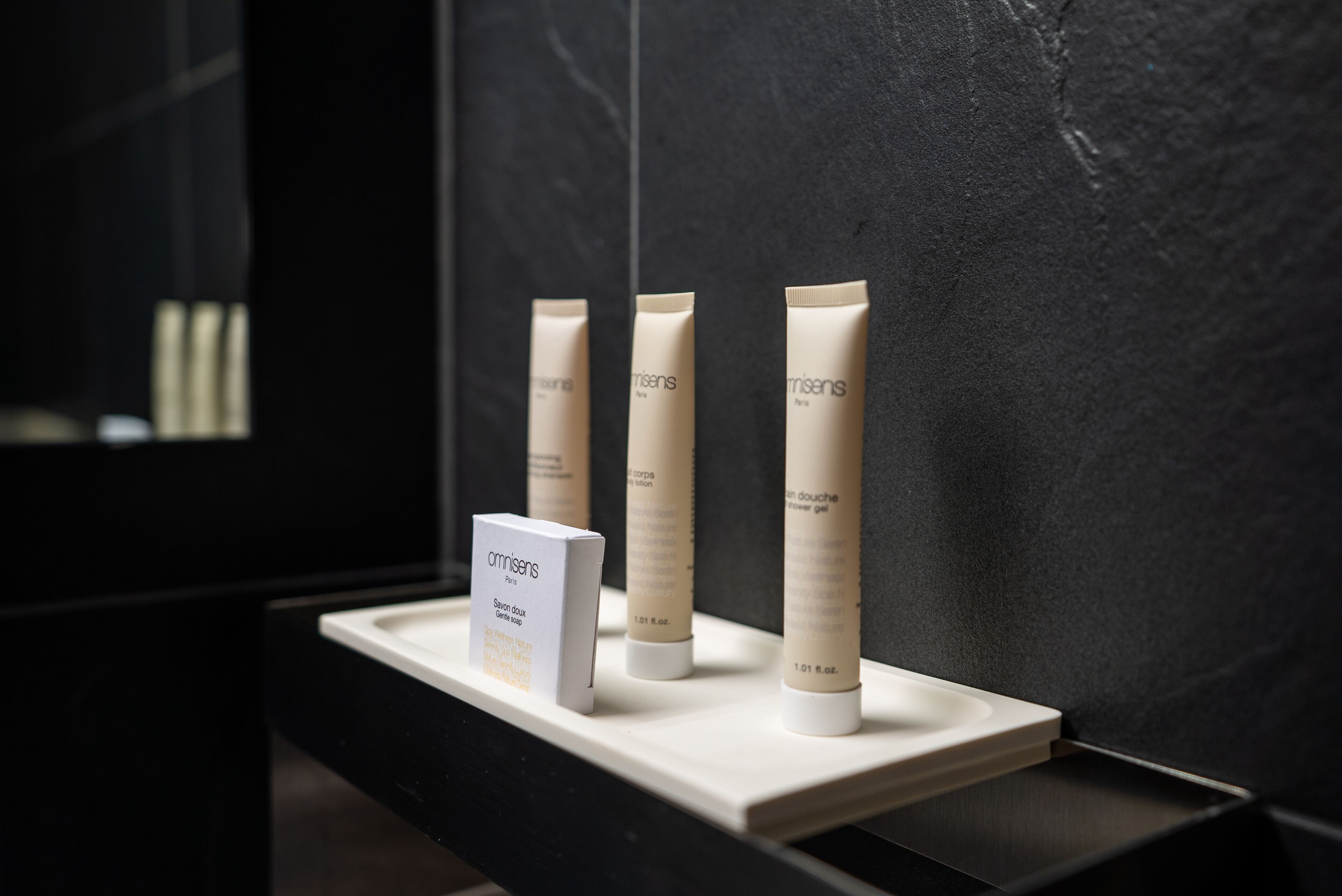 A display of Omnisens products on a white shelf against a dark wall.