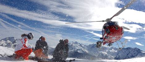 A group of people on a snowy mountain with a helicopter in the background.
