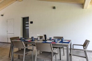 Un coin repas avec une table dressée pour quatre personnes, des chaises, une bouilloire et une porte dotée d’une serrure de sécurité.