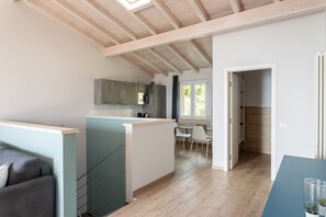 Une cuisine moderne avec un îlot central, un coin repas doté d’une table en verre et une vue sur l’extérieur grâce à une fenêtre.