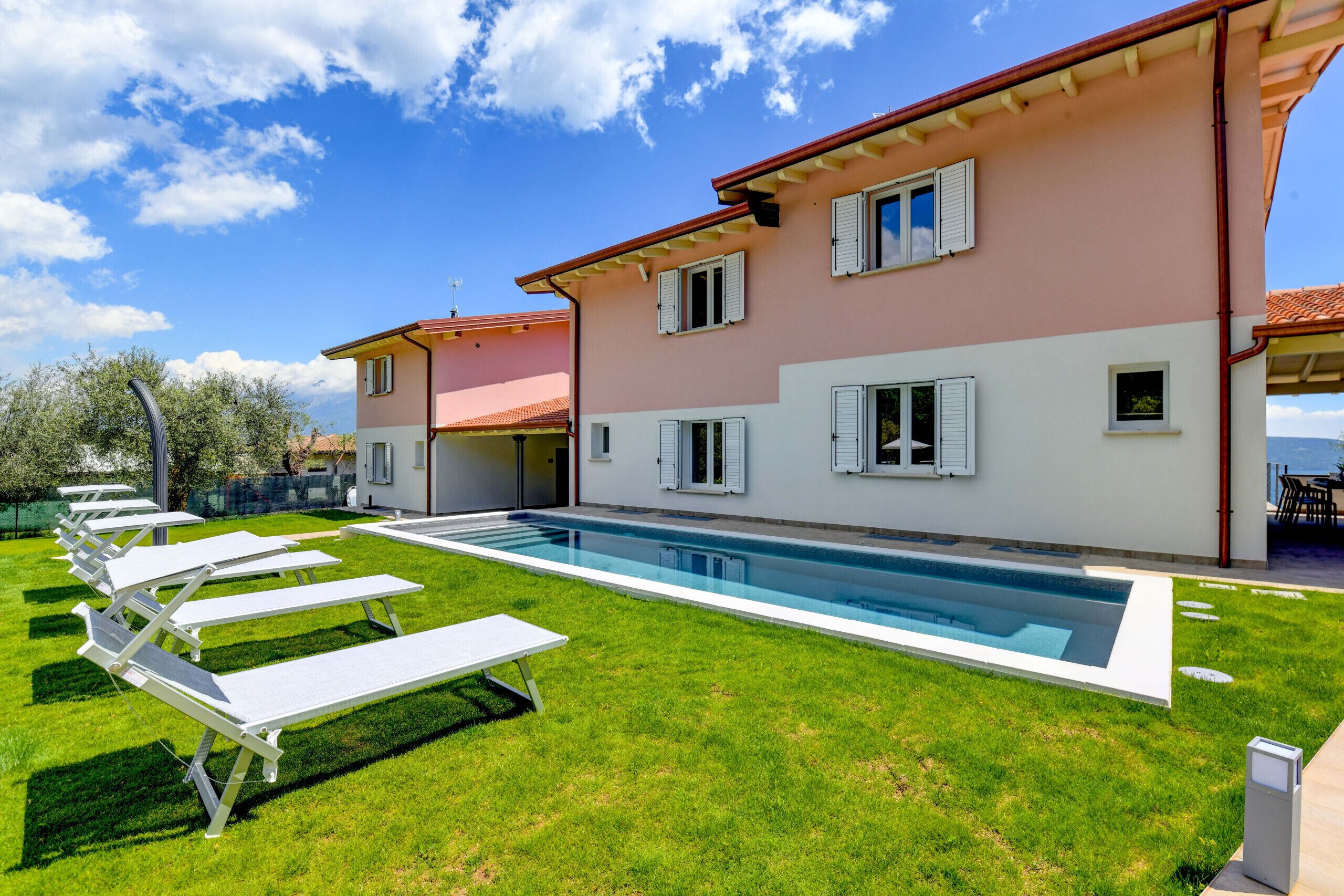 A two-story house with a swimming pool, white shutters, and a covered patio area.