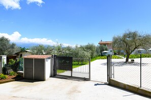 A gated entrance to a property with a clear view of the surrounding landscape, including trees and a distant building. - Le Casette - Casaliva with pool and lake view (Toscolano-Maderno)