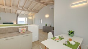 A modern kitchen with a wooden ceiling, a counter with a basket, and a dining area with a table set for two.