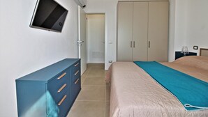 A bedroom with a bed, a dresser, a TV, and a wardrobe.