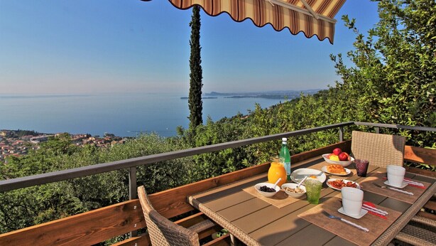 A terrace with a table set for breakfast, overlooking a coastal view.