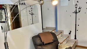 Un salon moderne avec un canapé inclinable, une lampe sur pied, une petite plante en pot et des autocollants décoratifs sur les murs.