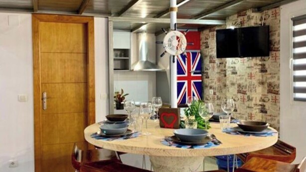 Un coin repas avec une table ronde, quatre chaises et un drapeau accroché au mur.