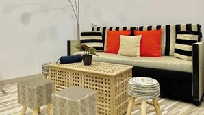 Un salon moderne avec un canapé, deux tables d’appoint et une lampe sur pied.