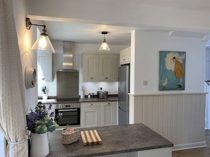 A modern kitchen with white cabinetry, stainless steel appliances, and pendant lighting.