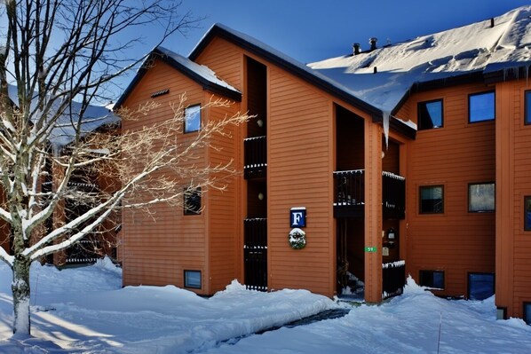 Un bâtiment moderne doté d’une façade en bois, d’une entrée bien visible et d’un panneau indiquant un espace de stationnement.