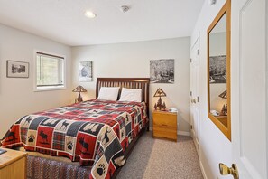Une chambre à coucher avec un grand lit, une table de chevet, une commode et un miroir.