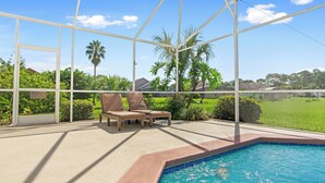 Un espacio exterior cubierto con piscina, sillas de descanso y vistas a un paisaje verde.