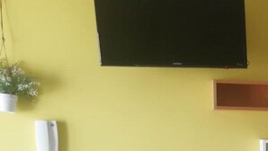 Un comedor con pared amarilla, sillas blancas y una mesa.