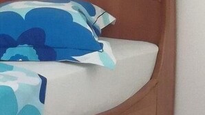 Una cama con cabecera de madera y una colcha blanca y azul estampada.