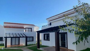 Un immeuble résidentiel moderne doté d’un patio couvert, d’une pelouse bien entretenue et surplombant un ciel bleu dégagé.