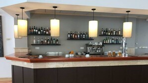 Un espace bar avec un comptoir, des étagères remplies de bouteilles et des luminaires suspendus.