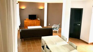 Un grand salon comprenant un canapé, une table à manger et un téléviseur.