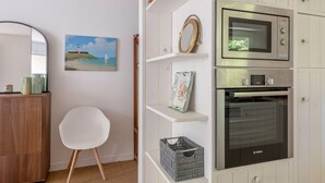 Eine Küche mit weißen Schränken, einem Bosch-Ofen und einem Korbwäscheschrank.