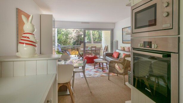Eine moderne Küche mit einem Backofen von Bosch, einem Essbereich mit einem roten Sitzsack und einem großen Fenster mit Blick auf einen Garten.