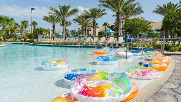 A pool area with multiple colorful inflatable rings and palm trees. - Private Movie Theater!  Up to 20 Guests! (Davenport)