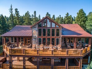 Eine große Holzhütte mit Steinverkleidung, mehreren Terrassen und Außenbereichen zum Sitzen.