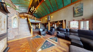 Un vestíbulo amplio con una escalera de madera, sofás de cuero y un área de comedor.