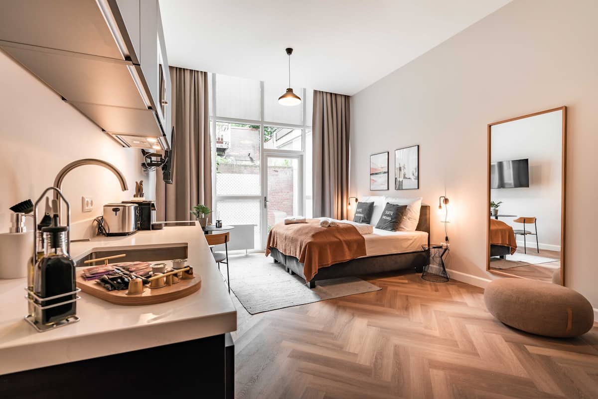 A modern bedroom with a large bed, bedside tables, a mirror, and a view of the outdoors.