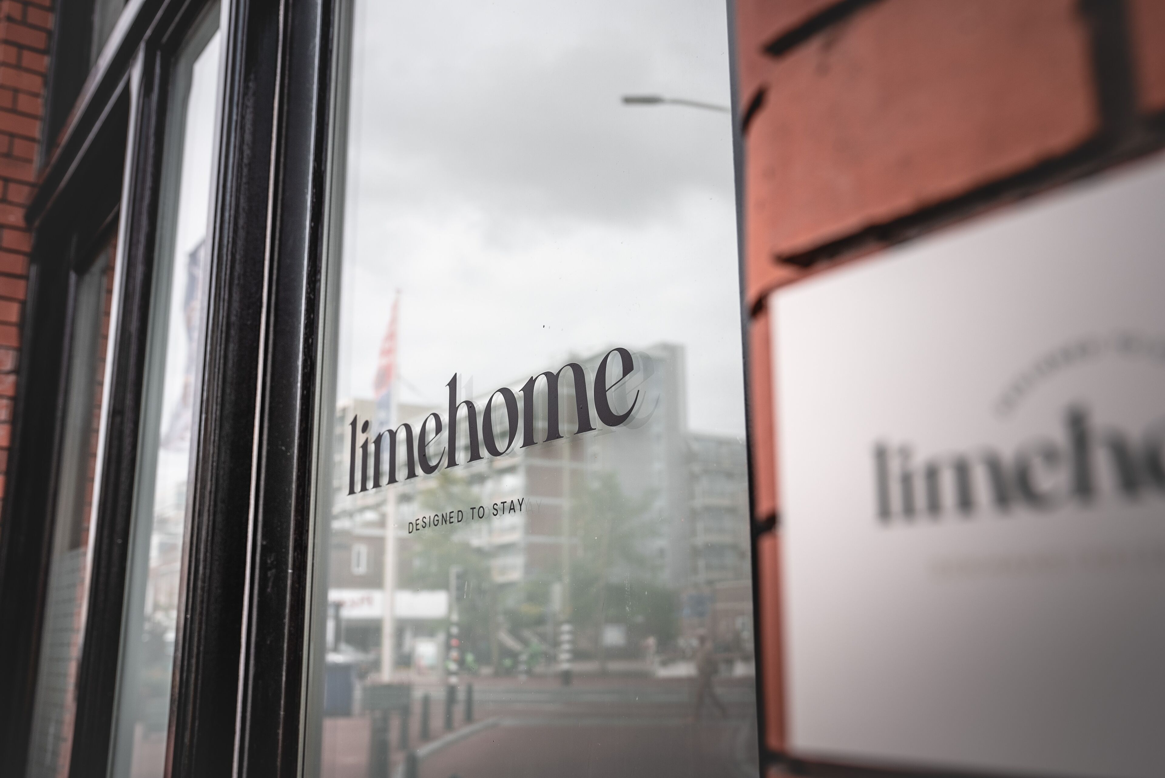 Une fenêtre sur laquelle on peut lire, à travers le verre, les mots « limenhome » et « DESIGNED TO STAY ».