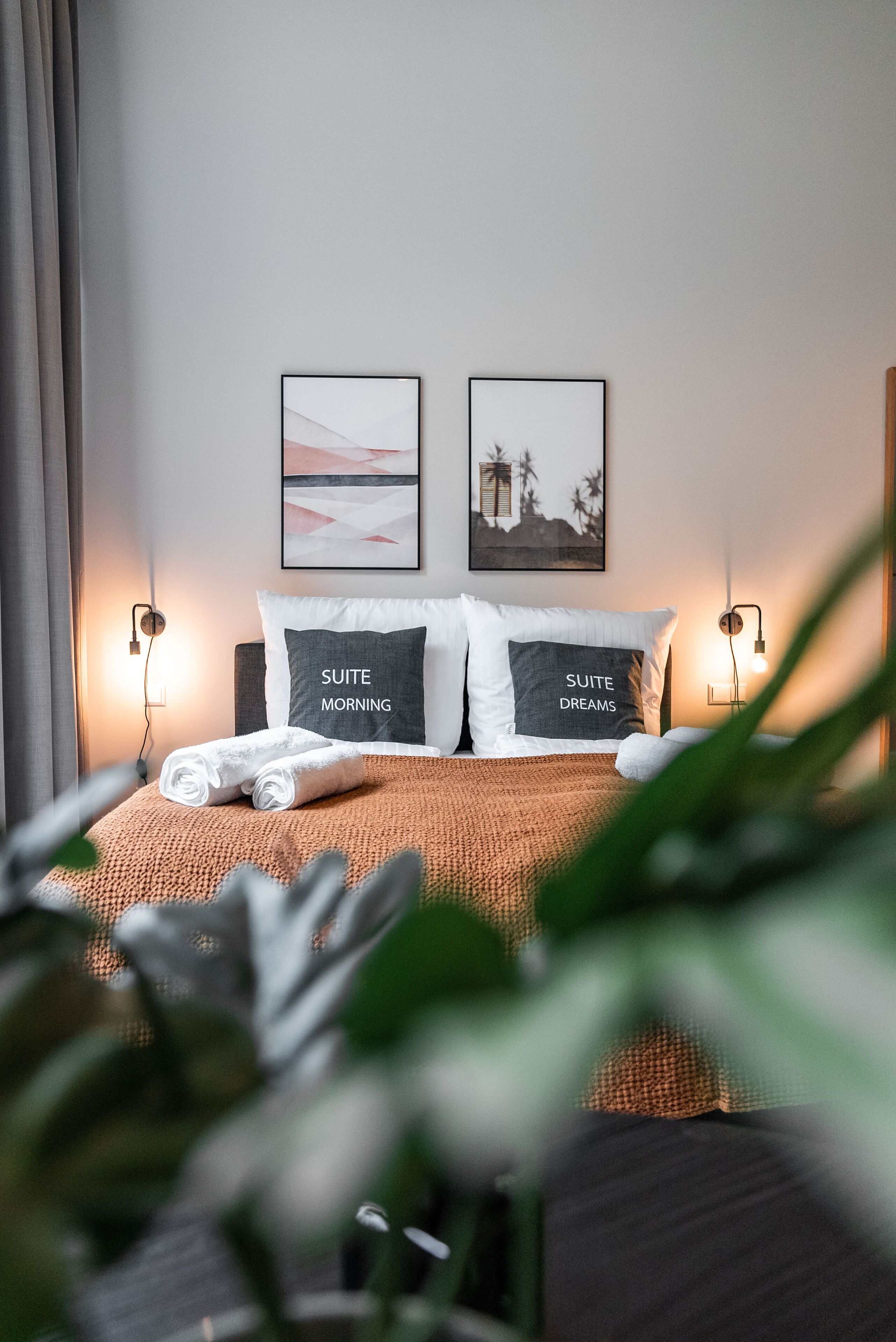 Een netjes opgemaakt bed met twee kussens, een bedlampje en een ingelijst foto aan de muur.