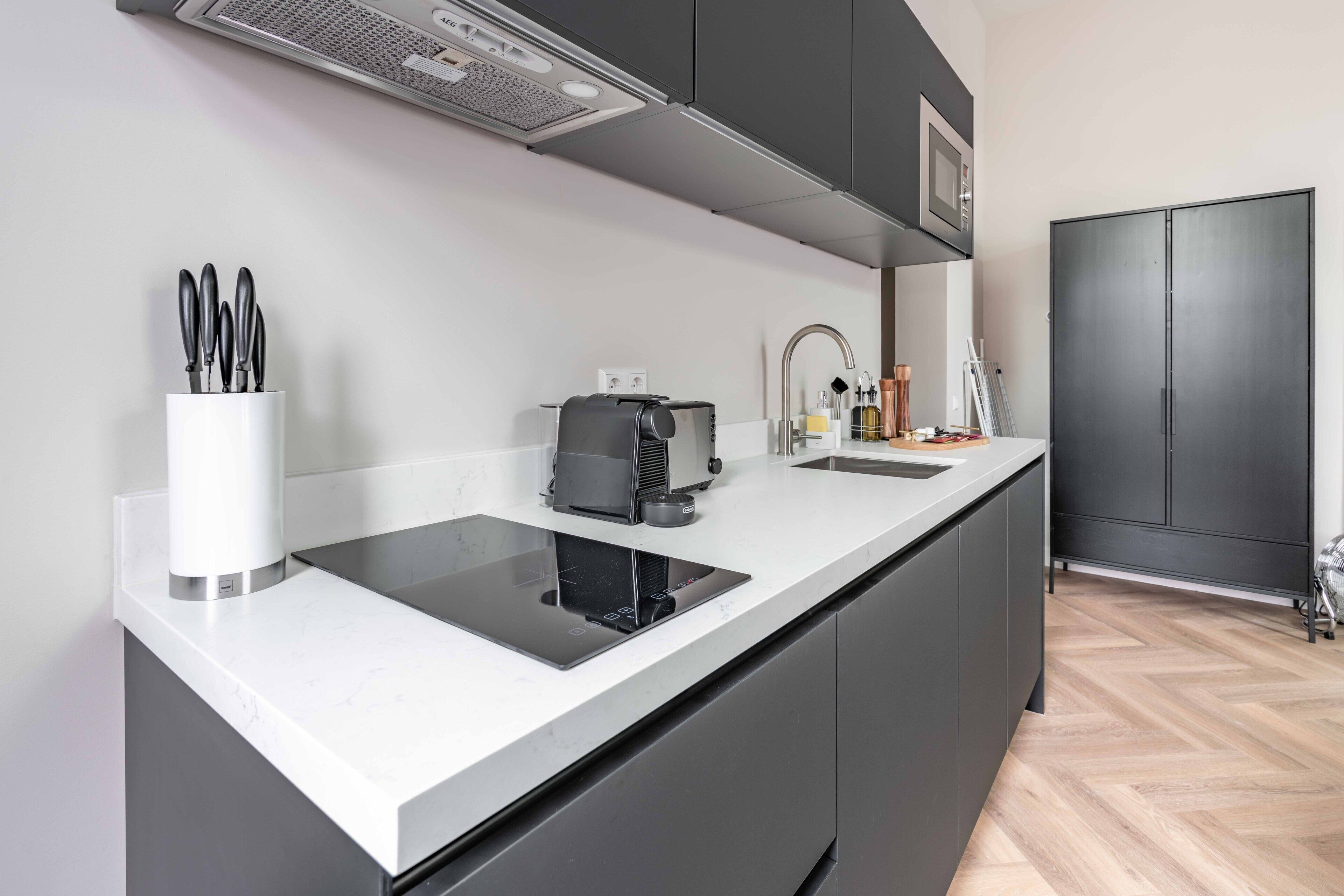 A modern kitchen with a built-in induction cooktop, a coffee machine, and a sink.