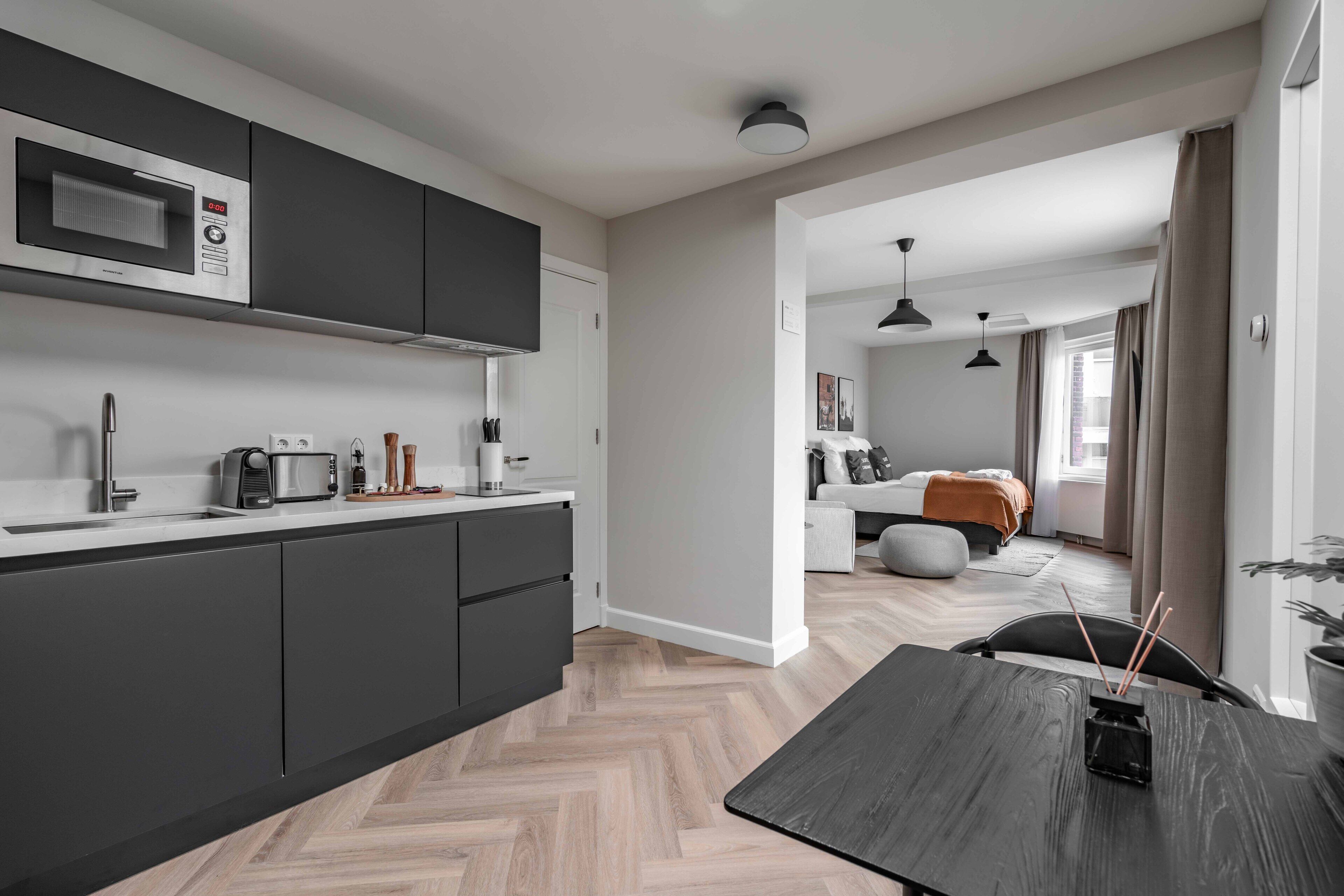 A modern kitchen with dark cabinets, a microwave, and a dining area with a table and chairs.