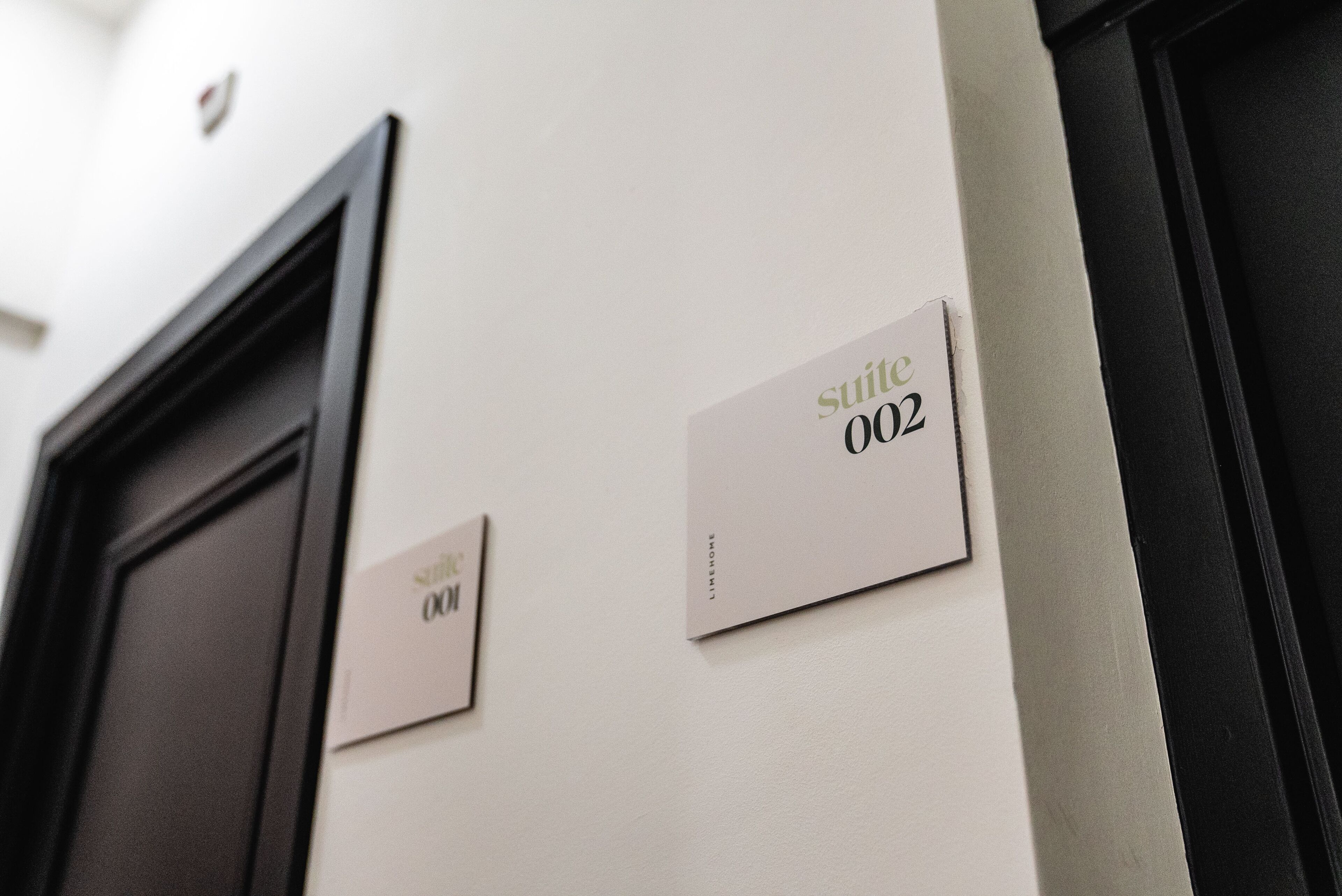 A hotel interior with a door and two signs indicating room numbers 002 and 001.