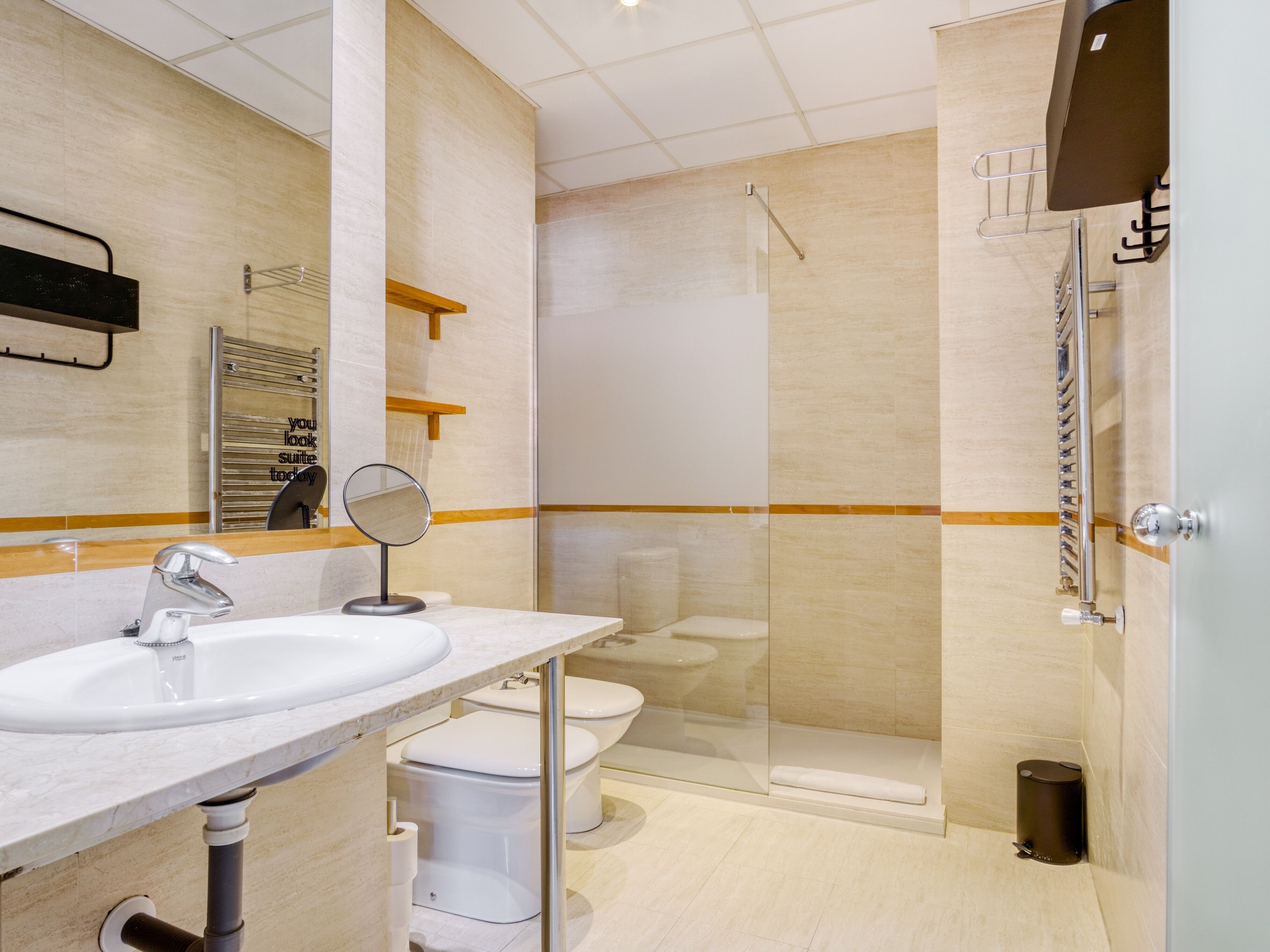 A modern bathroom with a sink, mirror, toilet, and glass-enclosed shower.