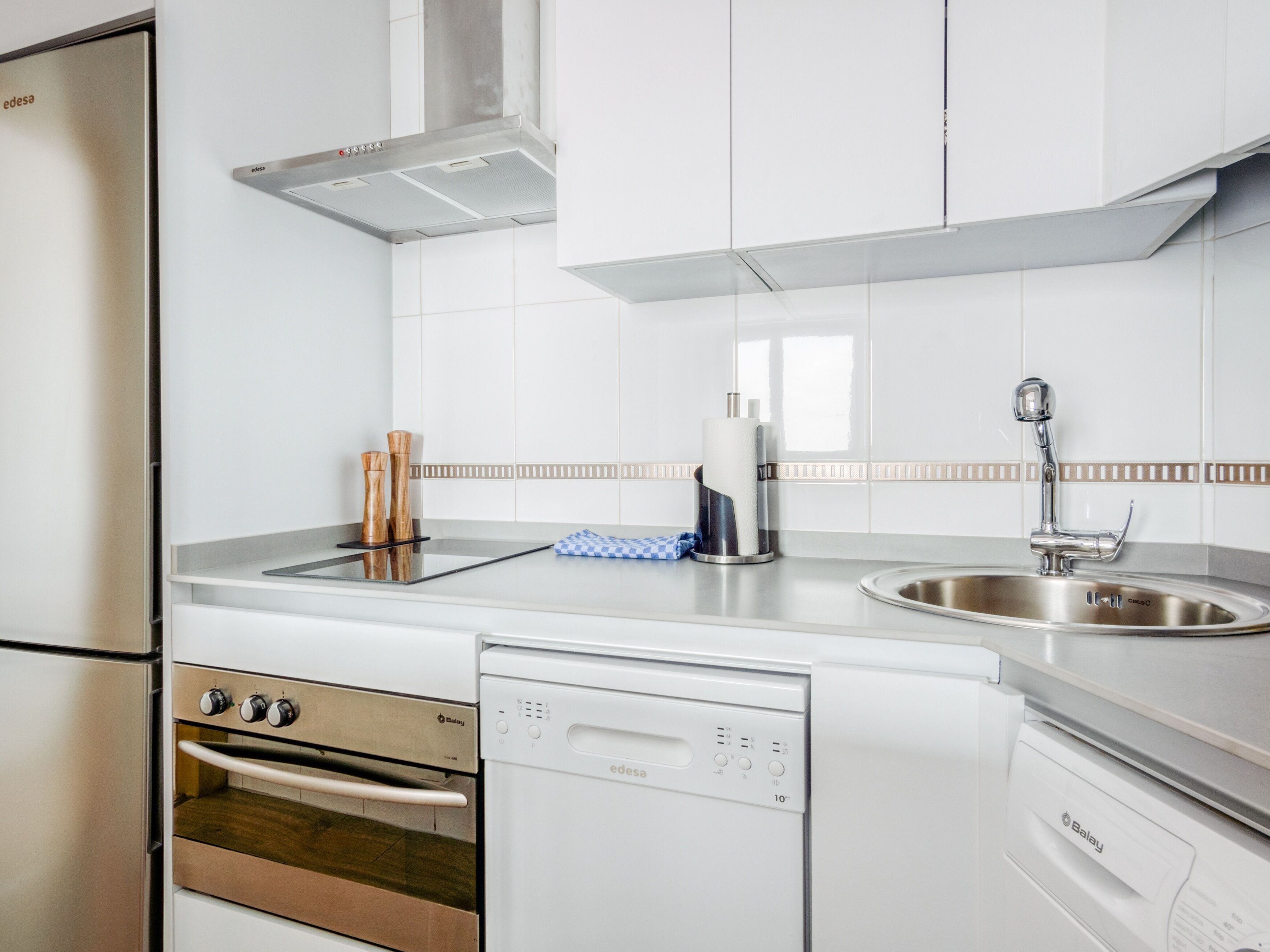 A modern kitchen with stainless steel appliances, including a dishwasher, oven, and sink.