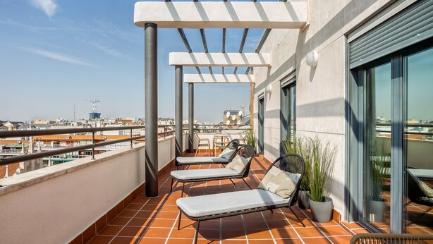 A rooftop terrace with two lounge chairs and a potted plant, overlooking a cityscape. - Limehome Madrid Calle de Don Ramón de la Cruz (Madrid)