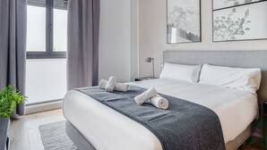 A modern hotel room with a large bed, grey curtains, a view of the outdoors, and two framed artworks on the wall. - Limehome Madrid Calle de Don Ramón de la Cruz (Madrid)