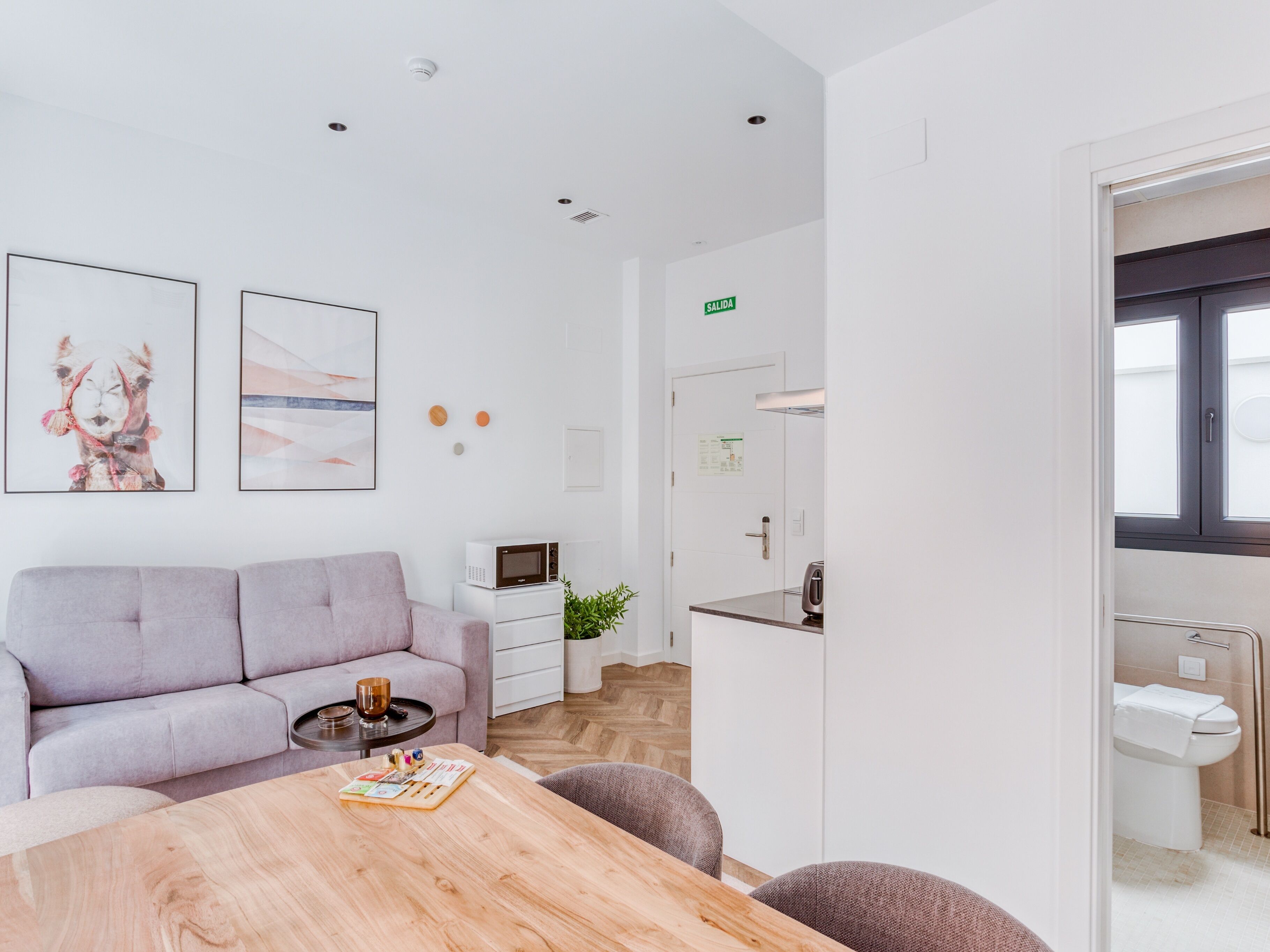 A modern living room with a sofa, a coffee table with a board game, a microwave, and a small plant.