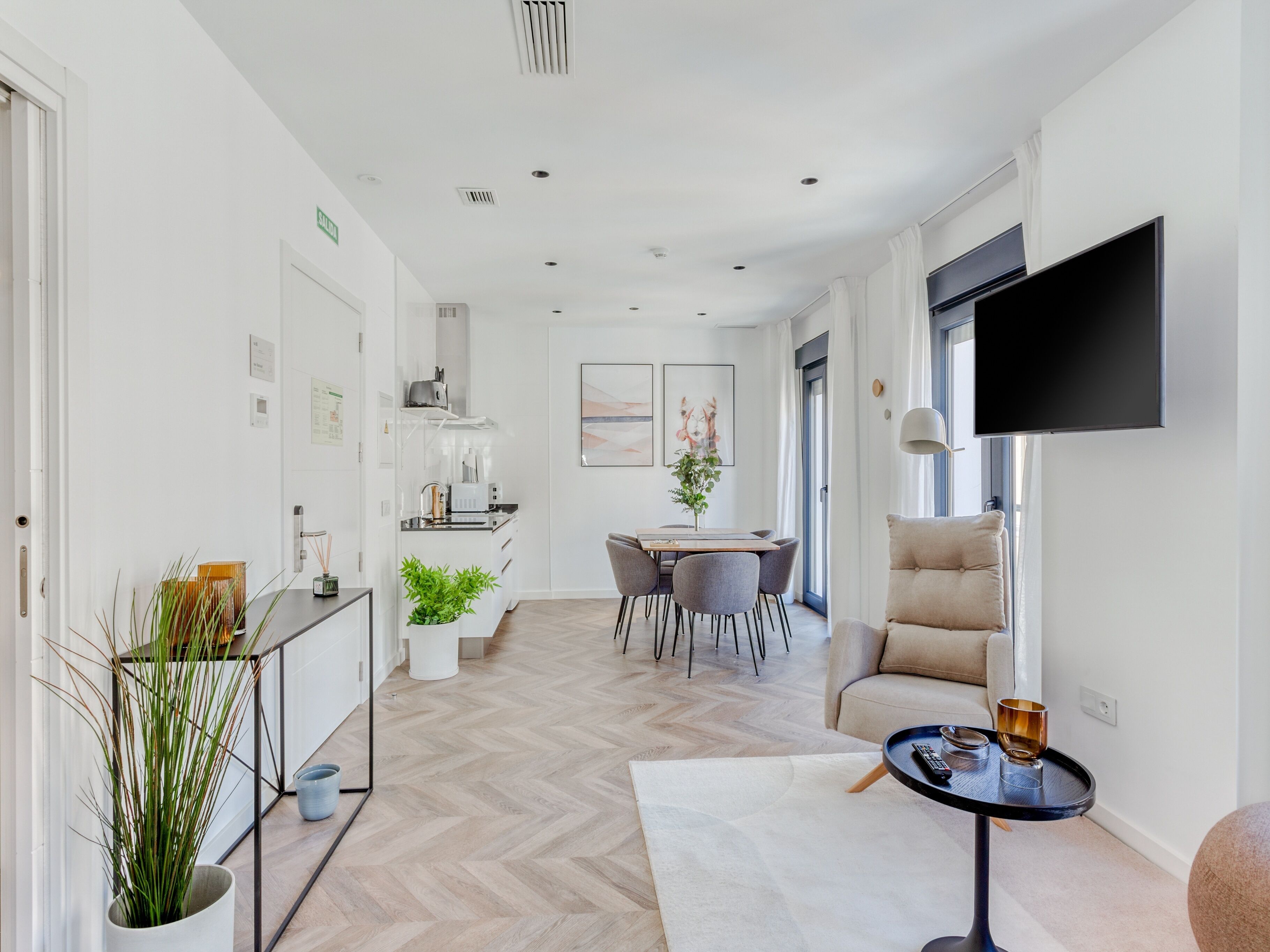 A modern living room with a sofa, a coffee table, and a TV mounted on the wall.