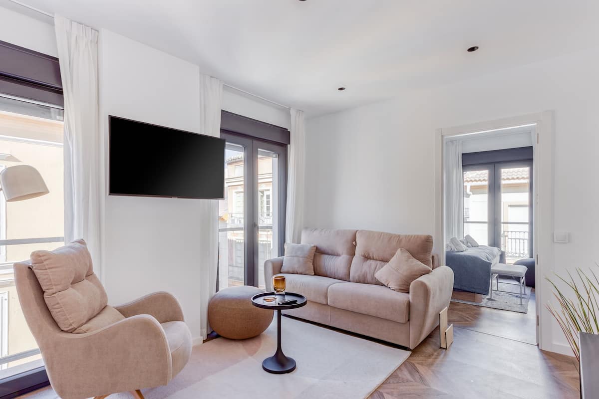 Ein modernes Wohnzimmer mit Sofa, Sessel und rundem Couchtisch.