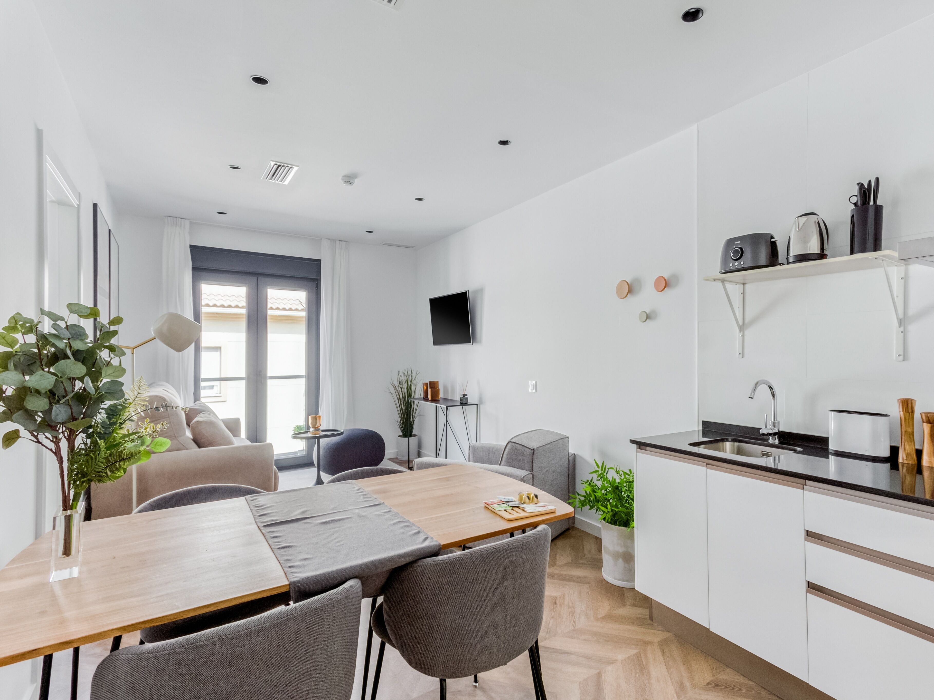 Una cocina moderna con armarios blancos, una mesa de comedor de madera y un horno empotrado.