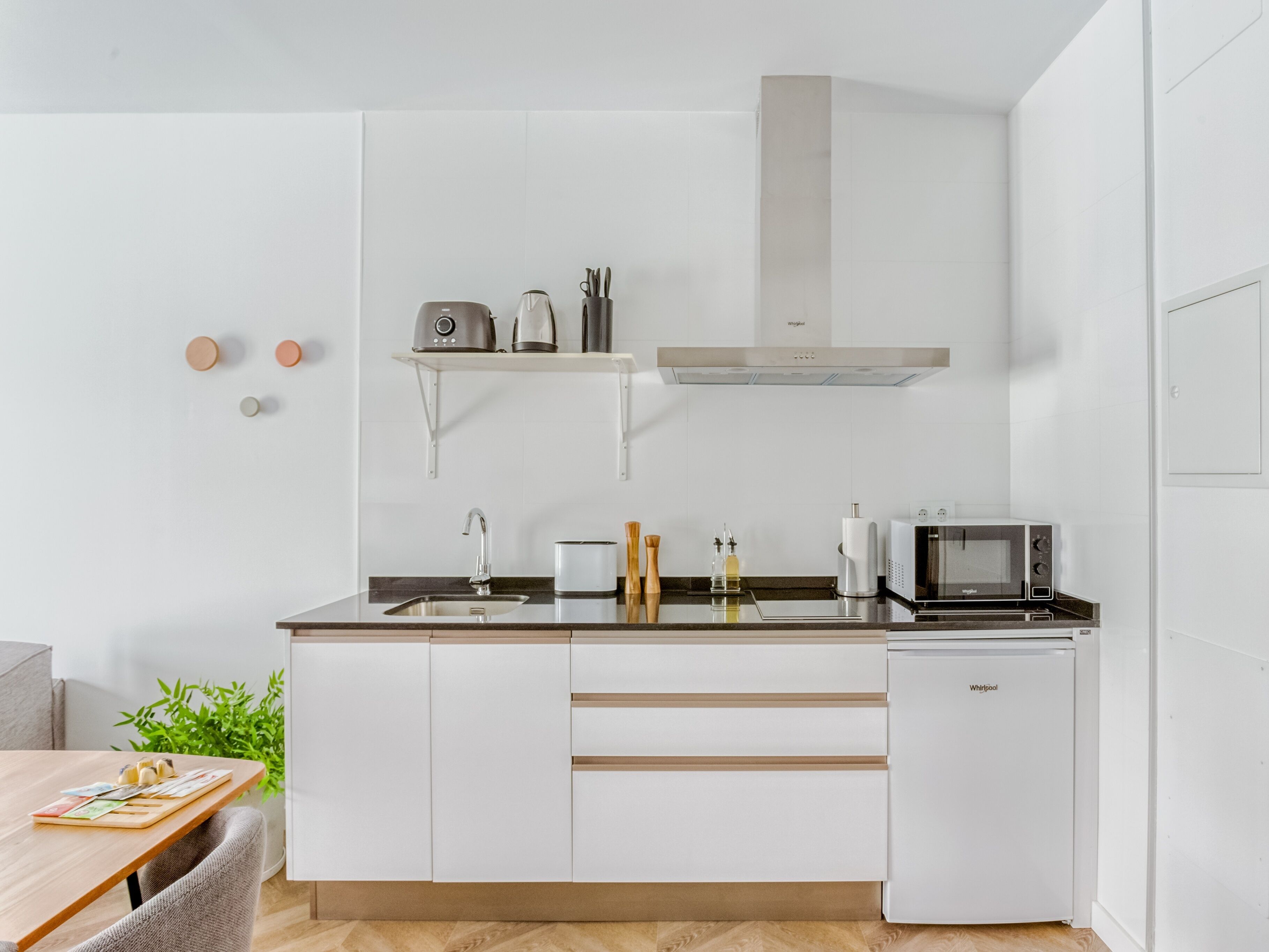 A modern kitchen with white cabinets, a built-in microwave, and a small refrigerator.