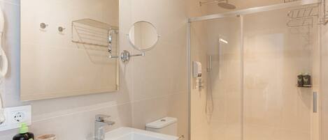 Une salle de bain moderne avec une douche à parois de verre, un meuble-lavabo à deux vasques et un grand miroir.
