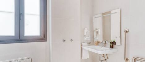 Un baño moderno con un ventanal grande, un lavamanos blanco, un espejo y una zona de ducha.