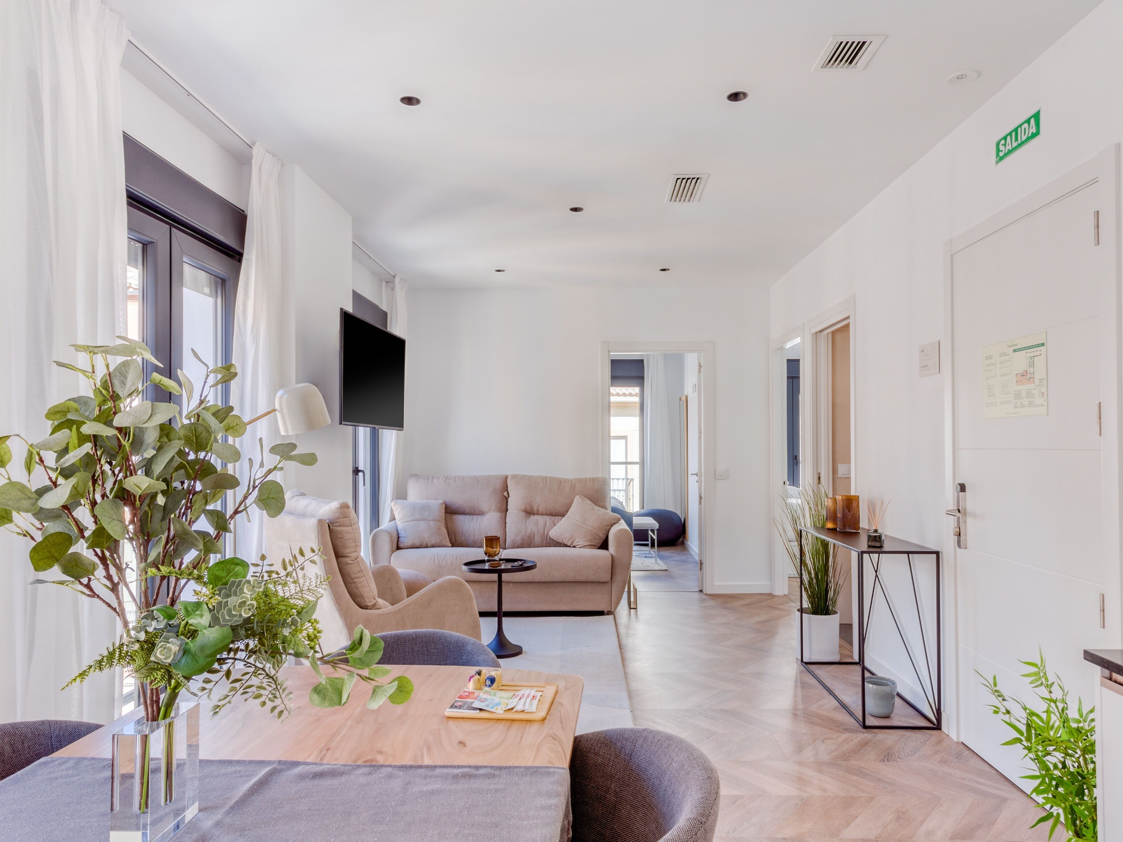 A modern hotel room with a sofa, a coffee table, and a TV.