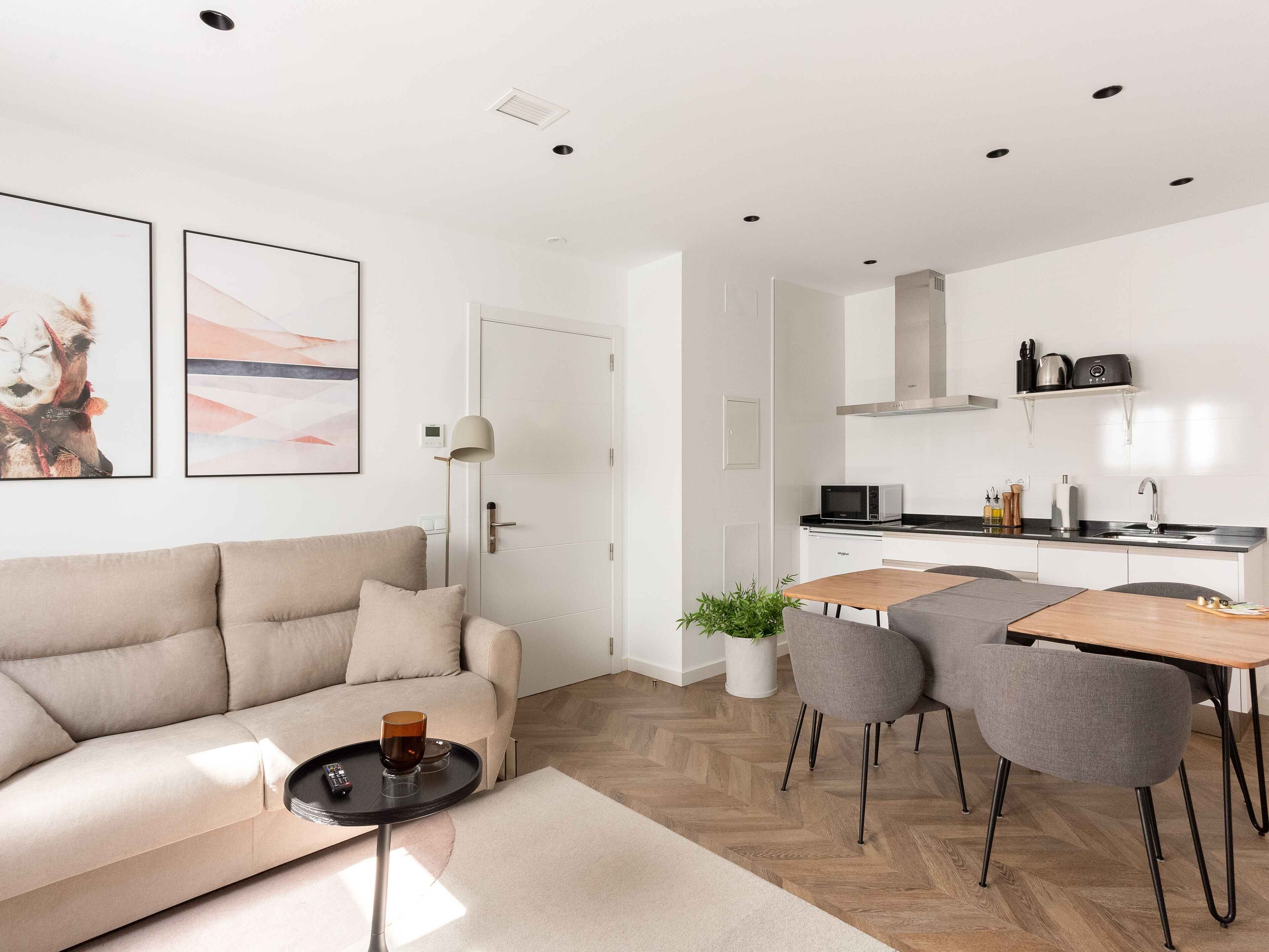 Una sala de estar moderna con sofá, mesa de centro y comedor con sillas y mesa.