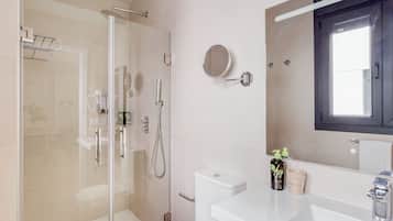 Un baño moderno con cabina de ducha de vidrio, un lavamanos blanco y un espejo sobre él.