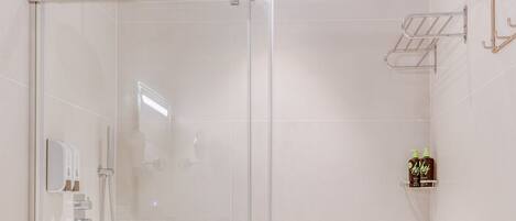A modern bathroom with a glass-enclosed shower, a white sink, and a towel rack.